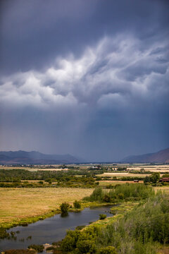 Dark storm clouds over fields and river