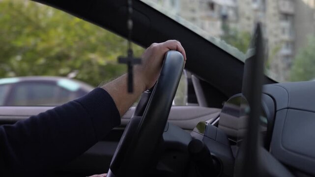Close-up inside a modern vehicle showing a driver gripping the steering wheel next to a large digital navigation touchscreen display