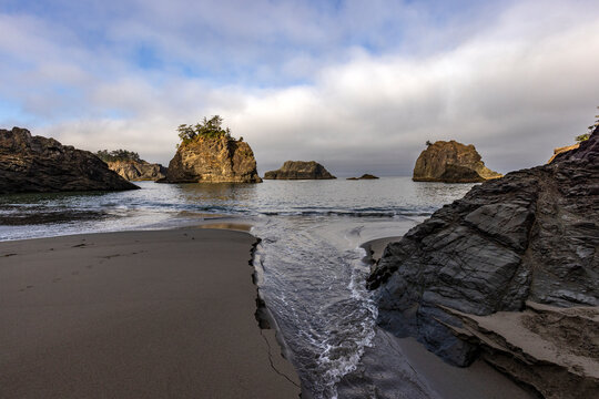 Tide running up creek channel on beach along Oregon Coast
