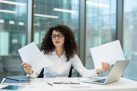 Stressed businesswoman comparing documents and dealing with office multitasking