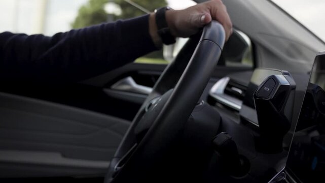 Close-up inside a modern vehicle showing a driver gripping the steering wheel next to a large digital navigation touchscreen display