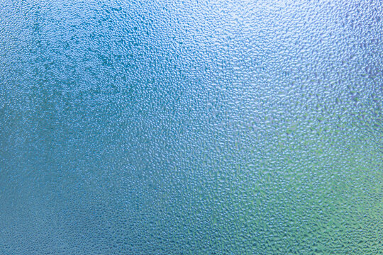 Condensation patterns on glass with cool tones