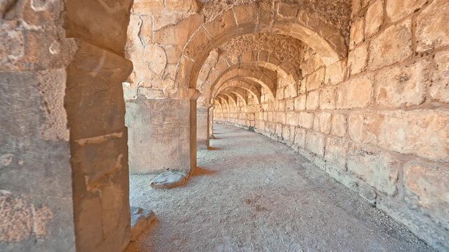 Aspendos Ancient City in Antalya, Turkiye, features a visitor walking among ancient stone columns, revealing its timeless Roman heritage.