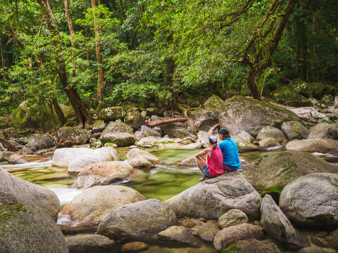 Rear view of couple sitting on boulder in Mossman River