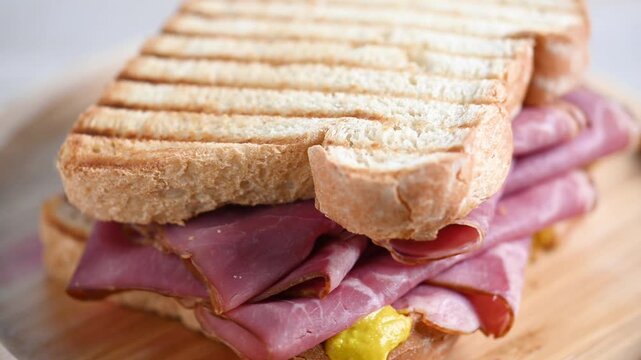 Rotating pastrami sandwich on wooden plate