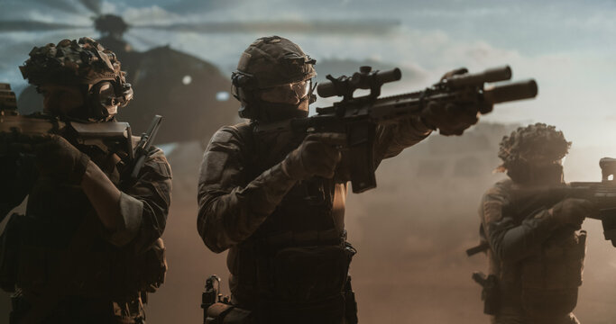Special Forces Squad Aims Suppressed Scoped Carbines Outward in Opposite Directions, Holding a Defensive Perimeter in Swirling Desert Dust as a Transport Helicopter Idles Behind Them.