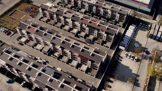 Ascending aerial footage of a contemporary apartment complex with organized rows of buildings and adjacent parking lots, showcasing the geometric patterns of modern suburban architecture