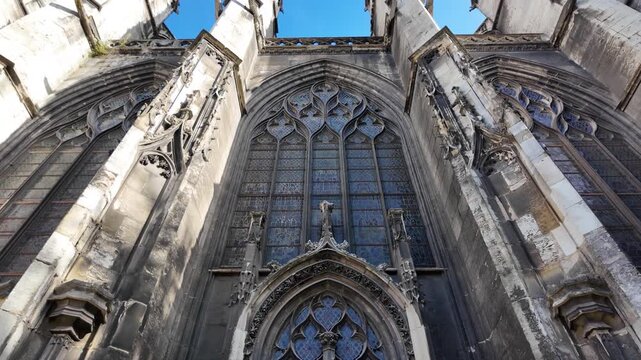 Upward view of Abbatiale Saint-Ouen in Rouen, France showing ornate Gothic tracery, carved stonework, pointed arches and tall stained glass windows