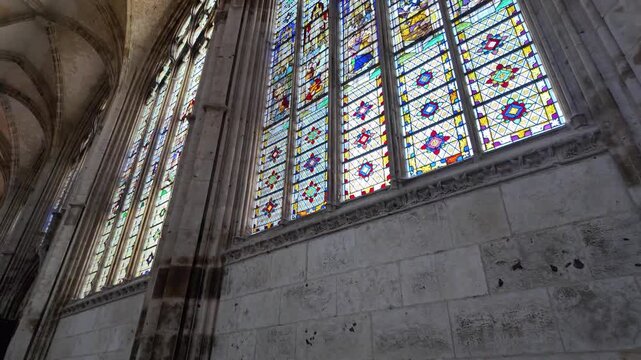 Slow motion view of colorful stained glass windows and stone masonry inside Abbatiale Saint-Ouen in Rouen, France