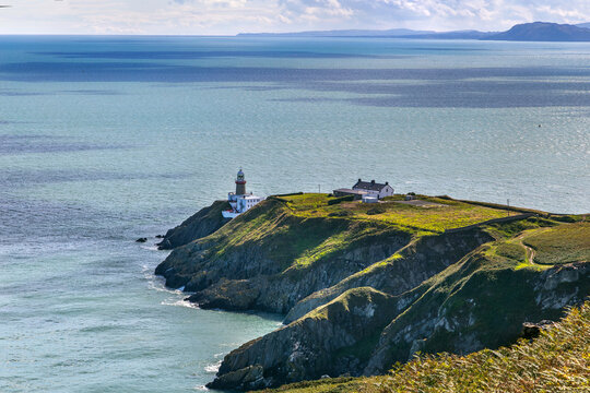 View of Howth Head peninsula with Baily Lighthouse in County Dublin, Ireland. Daytime shot of scenic coastal landscape