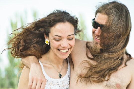 30s couple with hippie style smiling outdoors with sunset light in summer day