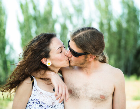 Young 30s hippie couple kissing outdoors in sunset summer day.