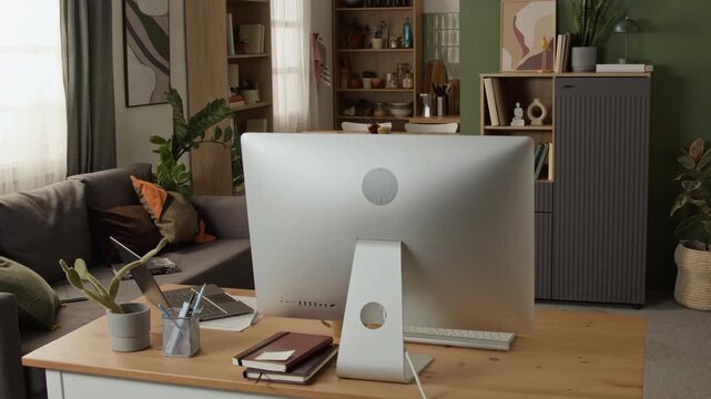 Empty modern home office desk with computer setup being shown during slow pan. Footage ideal for remote work campaigns, corporate presentations, and freelance concepts
