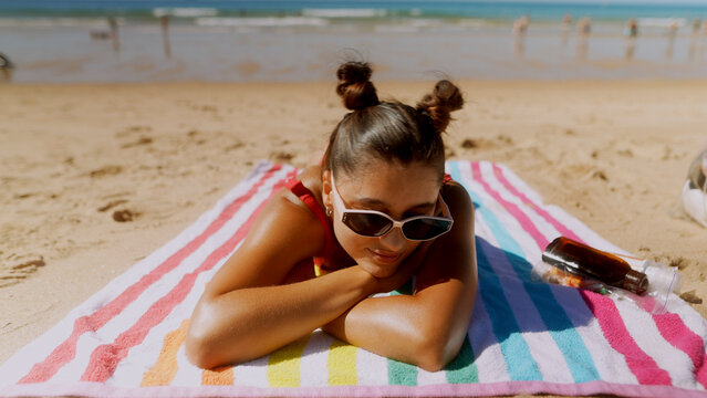 Woman in sunglasses resting her head on her arms at the beach