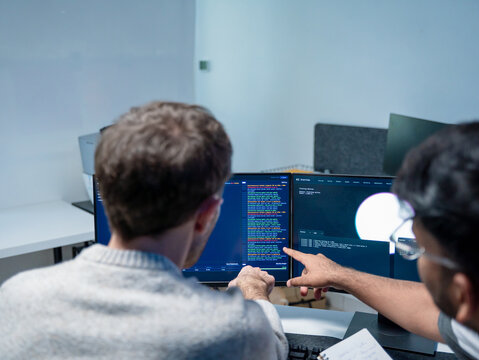 Professional programmers support the training of helping employee write code on computers for software AI development. Team engineer brainstorming is looking at coding cybersecurity analyzing website