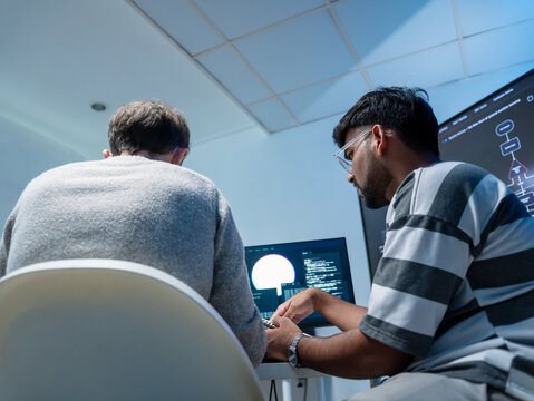 Professional programmers support the training of helping employee write code on computers for software AI development. Team engineer brainstorming is looking at coding cybersecurity analyzing website 