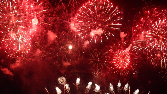 Vibrant red fireworks explode across the dark night sky with smoky textures, creating a festive background for Chinese New Year celebrations, Christmas, holiday events, and grand festivals