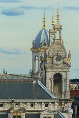 Decorative rooftop turrets with golden spires atop the historic Antwerp Central Station against a cloudy sky in Belgium. © hectorchristiaen