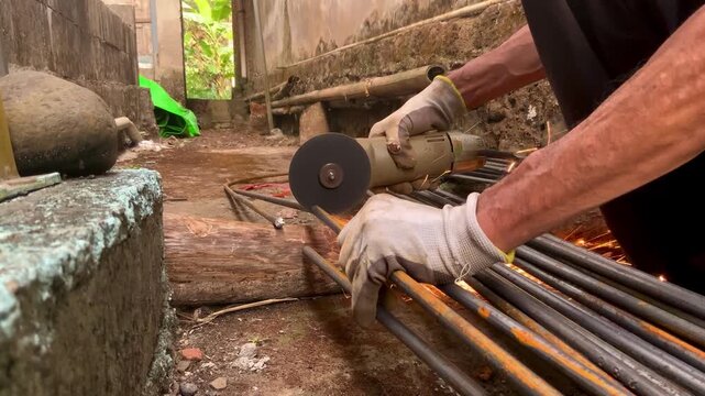 Construction worker using an angle grinder to cut steel rebar on a building site