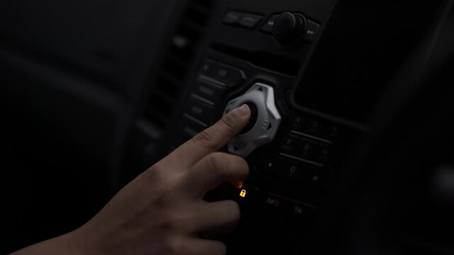Woman hand pressing the audio control button in a car.