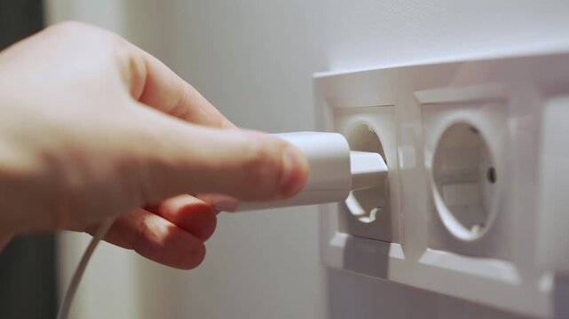 A person plugs a charging adapter and cable into a wall outlet.
Close-up of an electrical outlet in the wall.