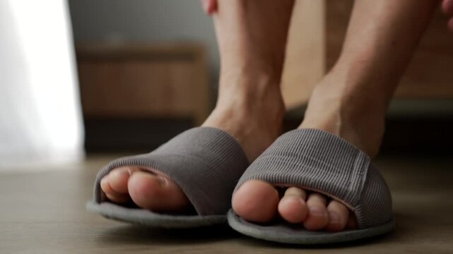 Close-up of slippers on feet. A person gets out of bed and puts on their slippers.