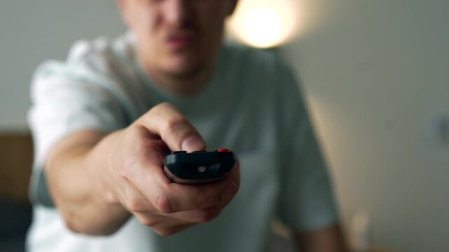 Annoyed Man Pressing Buttons on TV Remote Due to Technical Problems