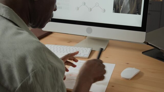 Senior African American businessman underlining printed document during online video conference on computer screen. Perfect for corporate training, remote work and business consulting projects