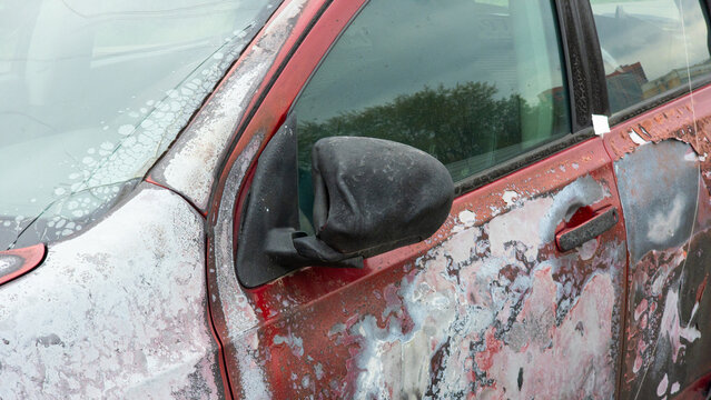 Passenger car with severely peeling and blistered paint caused by fire exposure, showing heat damaged bodywork and the aftermath of vehicle fire, automotive damage and restoration needs