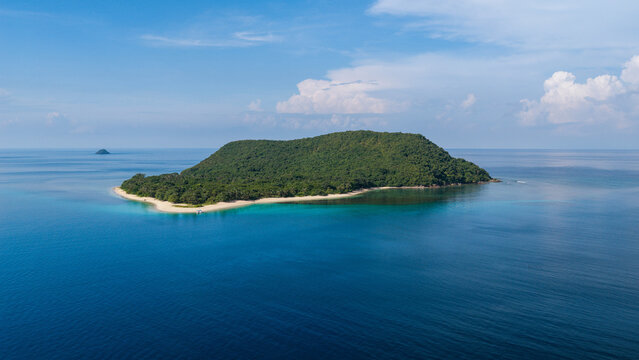 Aerial view of the lush green Busuanga island surrounded by turquoise waters and a white sand beach under a clear blue sky in Busuanga, Mimaropa, Philippines.