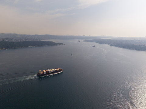 Aerial view of a large container ship navigating the Bosphorus strait, with calm dark blue waters and distant hilly coastlines in Istanbul, Istanbul, Turkiye.