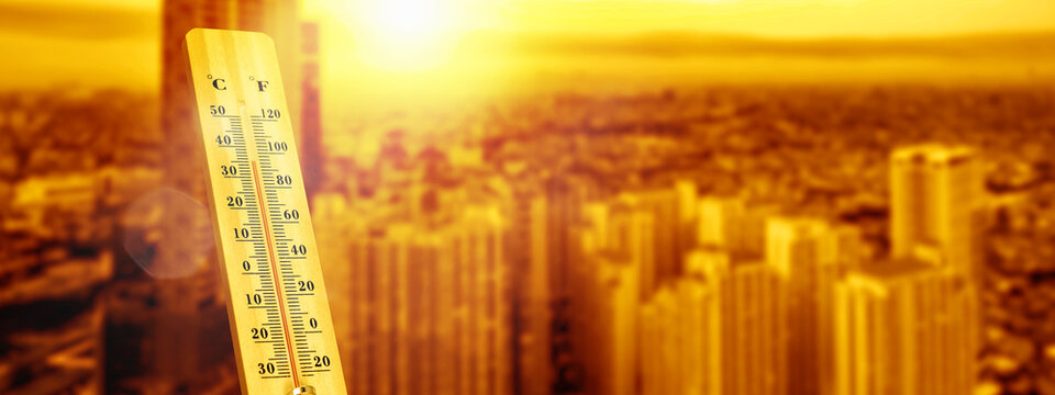 Wooden thermometer showing high temperatures against a warm, sunny cityscape background, representing heatwave and global warming concept.