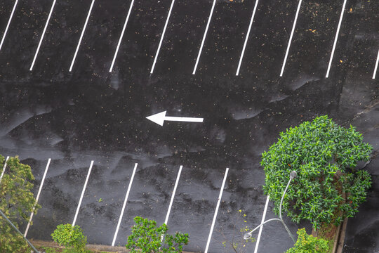 Aerial View of Parking Lot Spaces and Directional Arrow on Wet Surface