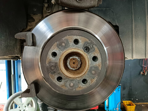 Automotive mechanic repairing a vehicle's brake disc rotor and wheel hub assembly. Brake system and steering knuckle repair in a car workshop. Car repair service showing brake disc, wheel hub, and ste