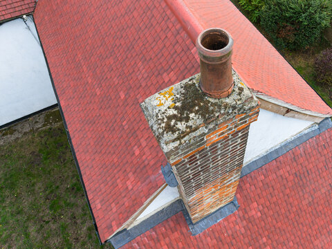 Interesting drone inspection view of a recently installed, terracotta-coloured roof seen on a renovated farm cottage in the UK. Note the high brick-built chimney, the chimney pot is showing its age.