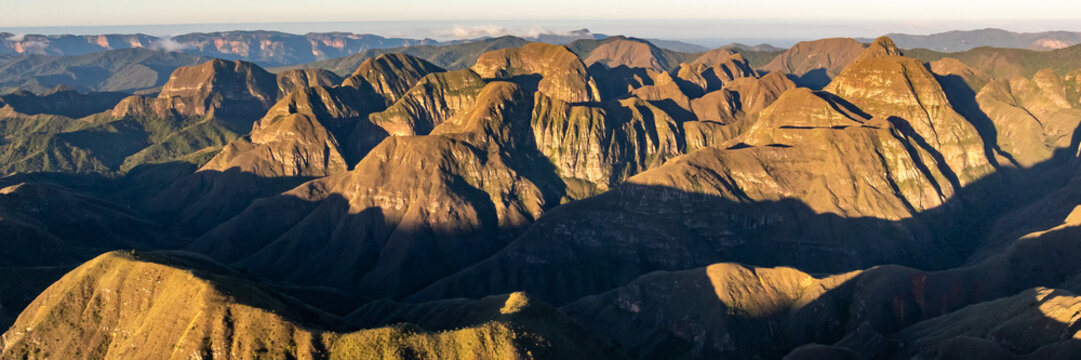 Aerial view of Codo de los Andes featuring rugged mountain peaks, deep valleys, and dramatic shadows cast by the golden hour light in Samaipata, Santa Cruz Department, Bolivia.