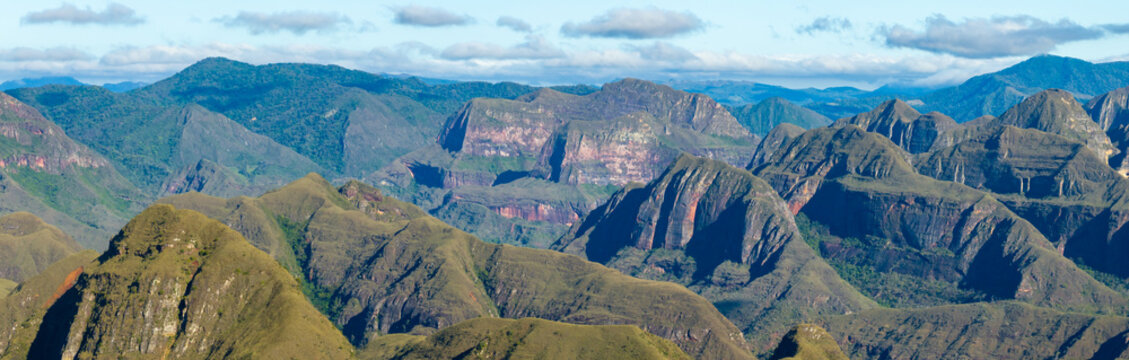 Aerial view of Codo de los Andes featuring rugged mountain peaks, deep valleys, and lush green slopes under a bright blue sky, Samaipata, Santa Cruz Department, Bolivia.