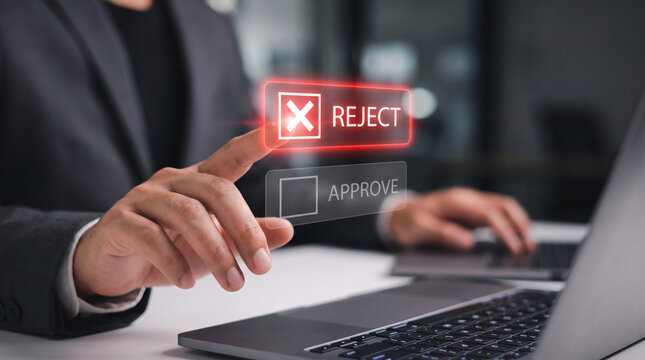 Businessman hand pressing virtual reject button on a digital interface screen while working on a laptop computer in a modern office environment