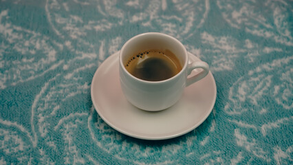 White cup of hot black coffee on a cozy blue patterned blanket © İdil Toffolo