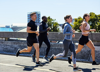 Naklejka premium Action, fitness and people running in city, marathon training for cardio and workout outdoor. Sport, athlete group or runner club with endurance, energy and exercise for race prep with practice