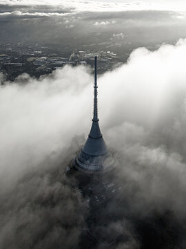 Aerial view of the iconic Jested Tower rising above a thick layer of clouds, with the surrounding landscape partially visible in the soft light, Liberec, Liberecky kraj, Czechia.