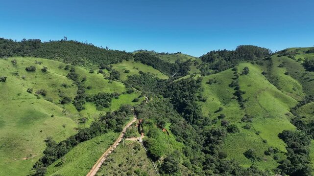 Vista a&eacute;rea de morros verdes e caminho rural em Cambu&iacute;