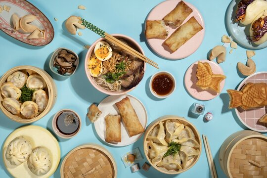 Traditional Chinese Dim Sum Feast with Dumplings, Steamed Buns, Rice Rolls and Asian Appetizers Arranged on a Blue Table, Overhead Food Photography