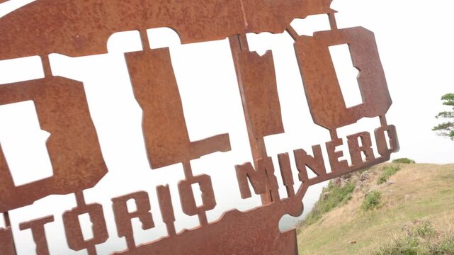 Close up of a rusted corten steel viewpoint sign at polio peak, mieres. The cutout text reveals the beautiful asturian mountain landscape