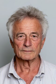 Close-up portrait of a senior man with calm demeanor and plain backdrop