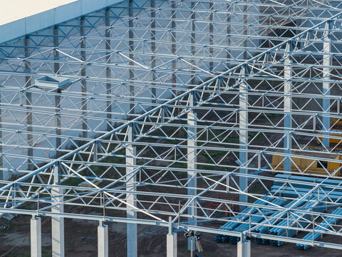 Aerial view of the steel roof structure of a warehouse under construction at the Genk-Zuid industrial site, featuring metal beams and building materials in Genk, Vlaanderen, Belgium.