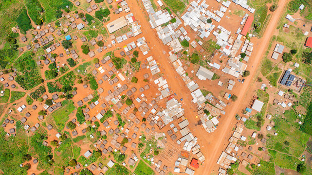 Aerial view of the village of Yumbe, featuring traditional round huts, metal-roofed structures, dirt roads, and surrounding green vegetation in Yumbe, Northern Region, Uganda.