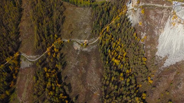 Drone cinematic panning shot from right to left comparing the new asphalt highway and the old winding road on Chike-Taman mountain pass.