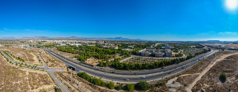 Aerial view of the highway infrastructure and surrounding urban landscape with green trees and buildings in Alicante, Valencian Community, Spain.