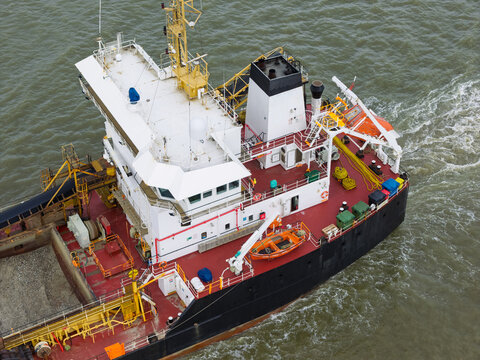 Aerial view of a large industrial ship with a white superstructure and black hull navigating through the water in the United Kingdom.